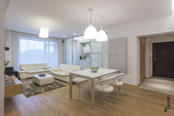 Moderne, helle Wohnküche mit weißen Möbeln und Holzboden.